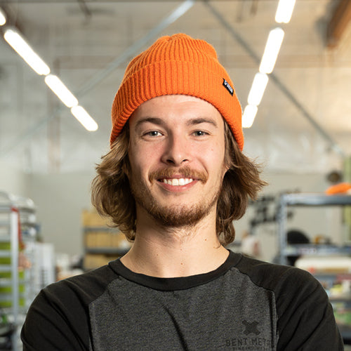 Man wearing an orange beanie with a logo indoors