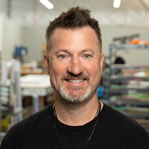 Man with a beard and short hair wearing a black shirt in an indoor setting.