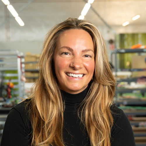 Woman with long blonde hair wearing a black turtleneck in a warehouse setting