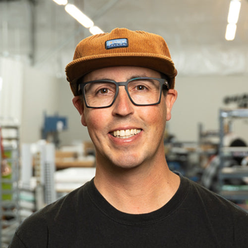 Man wearing a brown cap and glasses in an indoor setting