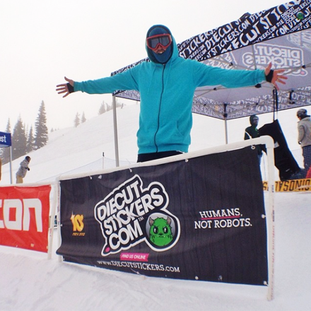 Person in a blue jacket with arms outstretched in front of a Diecut Stickers.com banner on a snowy background