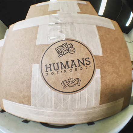 Cardboard box with a label reading 'Humans Not Robots' on a white surface.