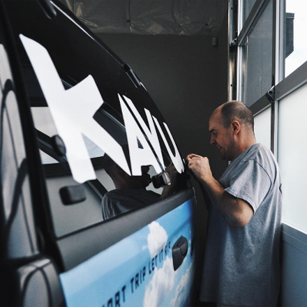 Person applying a large white logo on a vehicle door